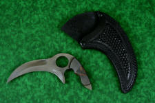 "Drepan" tactical karambit knife, obverse side view in T4 cryogenically treated 440C high chromium martensitic stainless steel blade, 304 stainles steel bolsters, orange/black G10 fiberglass epoxy composite laminate, sheath in leather shoulder, hand-tooled, nylon stitching, stainless steel reinforcement